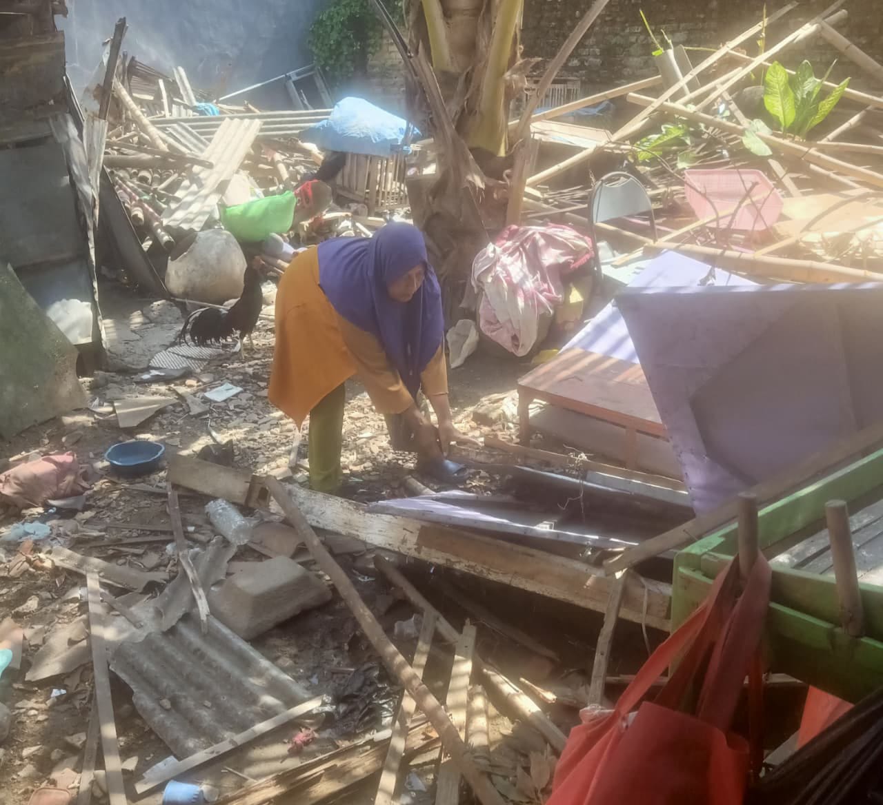 TAK DITEMPATI: Warga berada di balik reruntuhan rumah Hasanah yang terletak di Kelurahan Barkot, Kecamatan Kota Pamekasan.