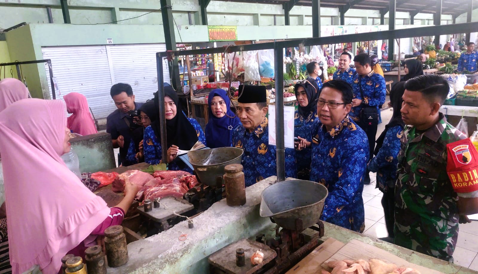 MONITORING: Ketua TPID Sampang Yuliadi Setiyawan (pakai peci) didampingi sejumlah pimpinan OPD meninjau harga daging di Pasar Rongtengah, Rabu (17/09).