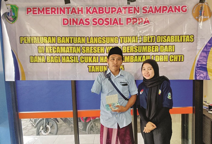 REALISASIKAN PROGRAM: Salah satu penerima bantuan disabilitas menunjukkan sejumlah uang usai mencairkan bantuan di kantor Bank Sampang Unit Sreseh Kamis (14/8). (DINSOS PPA UNTUK JPRM)