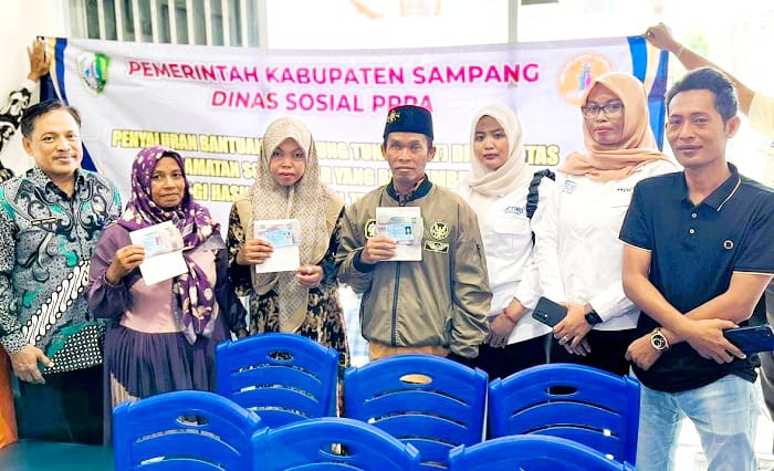 TEPAT SASARAN: Kabid Pelayanan dan Rehabilitasi Sosial Dinsos PPPA Sampang Zainal Muttaqien berfoto bersama penerima bantuan di Kecamatan Sokobanah, Rabu (27/8). (DINSOS PPPA UNTUK JPRM)