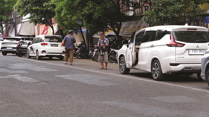 CAPAIAN RENDAH: Seorang jukir yang bertugas di ruas Jalan KH Moh. Kholil Bangkalan sedang mengawal kendaraan warga Jumat (26/9). (VIVIN AGUSTIN HARTONO/JPRM)