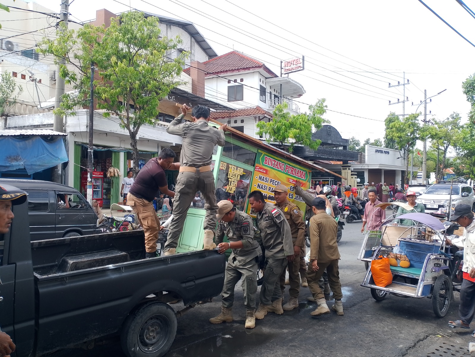 NAKAL: Anggota Satpol PP mengamankan rombong PKL yang mokong berjualan di Jalan Rajawali, Sampang, Selasa (30/9), pukul 08:44.