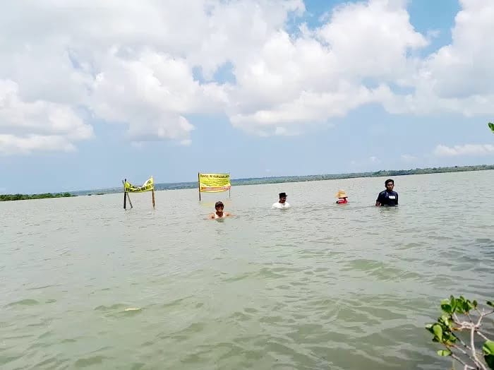 PEDULI LINGKUNGAN: Warga memasang poster kawasan lindung di pantai yang rencananya akan digarap menjadi tambak garam, di Pantai Tapakerbau, Desa Gersik Putih, Sumenep. (DOK/JPRM)