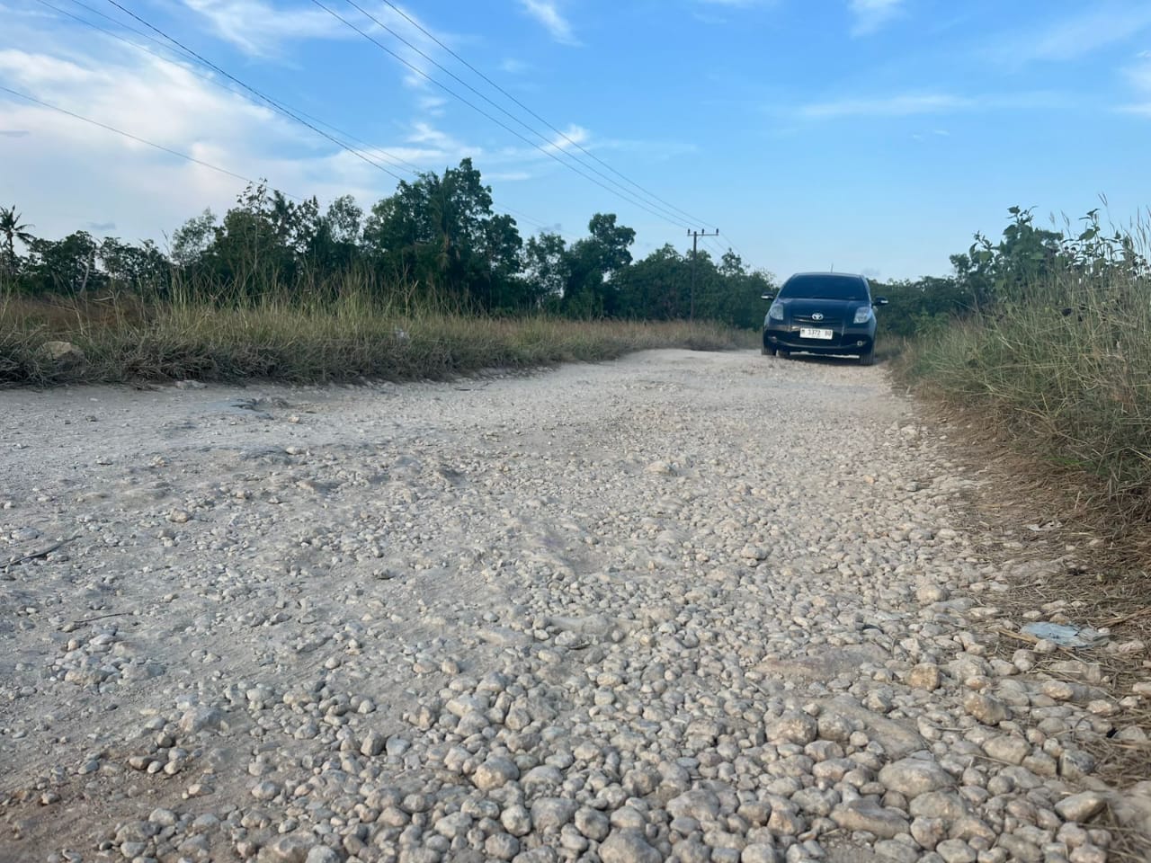 RUSAK PARAH: Pengemudi mobil sedang melintas di akses jalan penghubung dua kecamatan di Desa Giring, Kecamatan Manding, Minggu (5/10).