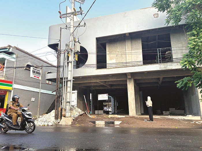 DISITA: Seorang perempuan membaca plang penyitaan bangunan milik terduga pelaku TPPU narkotika di Jalan KH Moh. Kholil Bangkalan Senin (6/10).