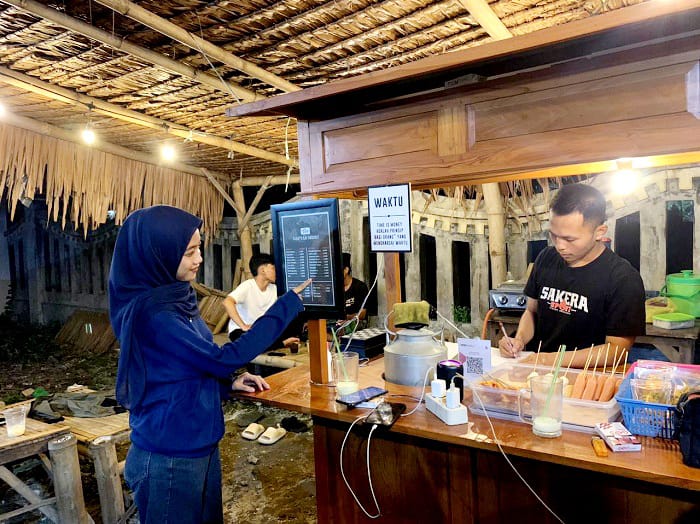 PILIH MENU: Pelanggan angkringan Gubuk Kopi sedang melihat menu, Kamis (16/10). (M. KHOLIL RAMLI/JPRM)