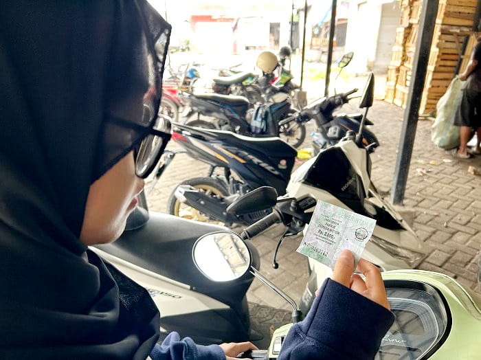 BERNILAI EKONOMIS: Seorang perempuan menunjukkan karcis parkir di Pasar Ki Lemah Duwur Bangkalan Senin (3/11). (VIVIN AGUSTIN HARTONO/JPRM)