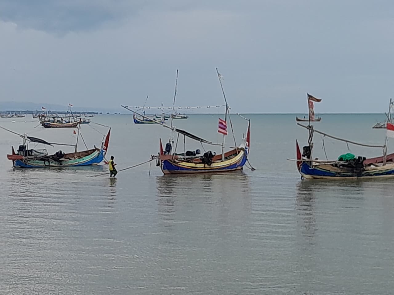 BERSANDAR: Seorang nelayan beraktivitas di sekitar sampan di pesisir Pantai Talang Siring, Pamekasan, Senin (3/11).