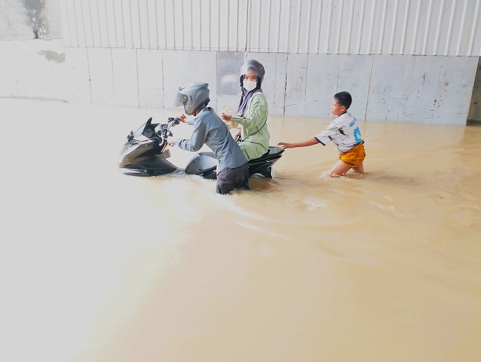 MOGOK: Pengendara mendorong motornya menerobos banjir di jalan raya depan Ponpes Nata Prajjan, Sampang, Kamis (6/11). (UBAIDILLAHIR RAIE/JPRM)