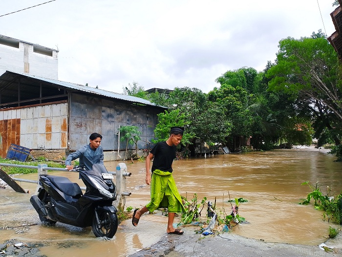 MELUAP: Warga melintas di jembatan sungai Desa Prajjan, Kecamatan Camplong, Sampang, Kamis (6/11). (UBAIDILLAHIR RAIE/JPRM)