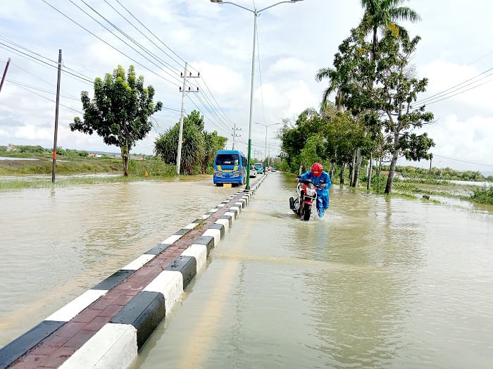 BUTUH PENANGANAN: Pengguna jalan mendorong kendaraannya di Jalan Sumenep&ndash;Pamekasan yang terendam banjir pada Rabu (14/5). (MOH. LATIF/JPRM)