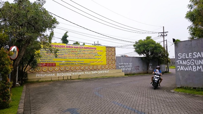 DIDUGA BERMASALAH: Pemotor melintas di depan pintu masuk Perumahan Griya Anugerah Bangkalan Senin (17/11). (ZEINAL ABIDIN/JPRM)