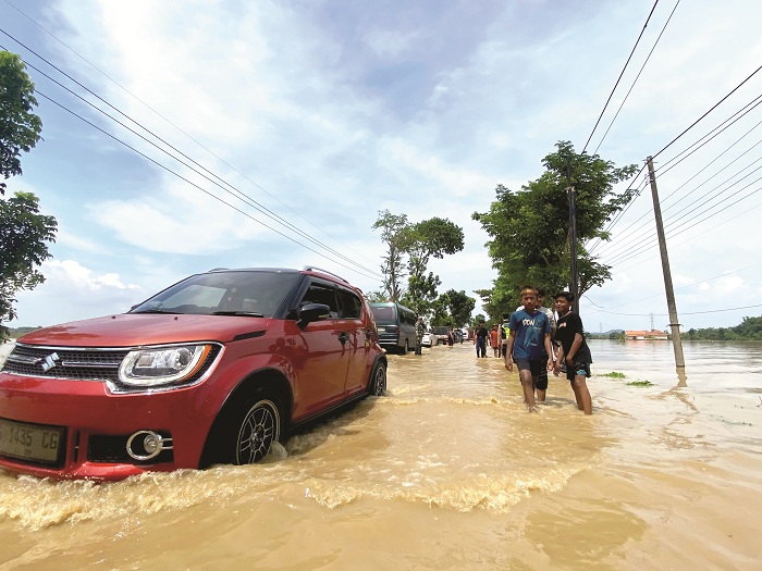 BANJIR: Pengendara motor berhati-hati saat melintasi genangan air di Jalan Raya Jrengik, Sampang, Rabu (19/11). (AYU LATIFAH/JPRM)