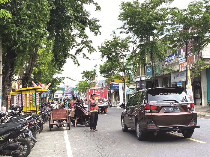 PENERTIBAN: Jukir saat membantu pengendara motor menyeberang di Jalan Panglima Sudirman Kamis (20/11). (AYU LATIFAH/JPRM)