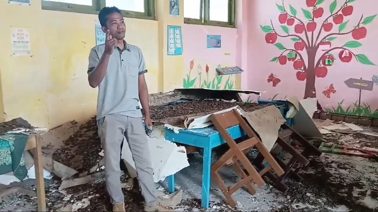 BUTUH PERBAIKAN: Seorang guru menunjukkan kondisi ruang kelas yang rusak terdampak gempa di Pulau Sapudi, Sumenep.
