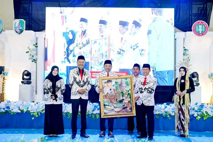 SIMBOLIS: Bupati Slamet Junaidi mendapatkan penghargaan lukisan pada kegiatan puncak HUT PGRI Sampang dan HGN Ke-80 di Gedung PKPRI Sampang Minggu (23/11). (DISKOMINFO UNTUK JPRM)