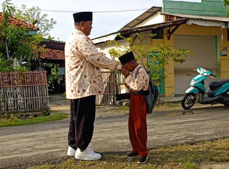 PENDIDIK: Jazuli menunggu kedatangan siswanya di depan SDN Kropoh 1, Kecamatan Raas, Sumenep.