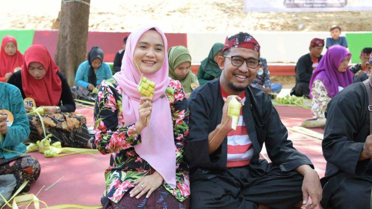 SERASI: Bupati  Fauzi  beserta istrinya, Nia Kurnia Fauzi, saat membuat selongsong ketupat di festival ketupat yang terselenggara di tempat wisata Pantai Slopeng, Kecamatan Dasuk pada Senin (7/4).