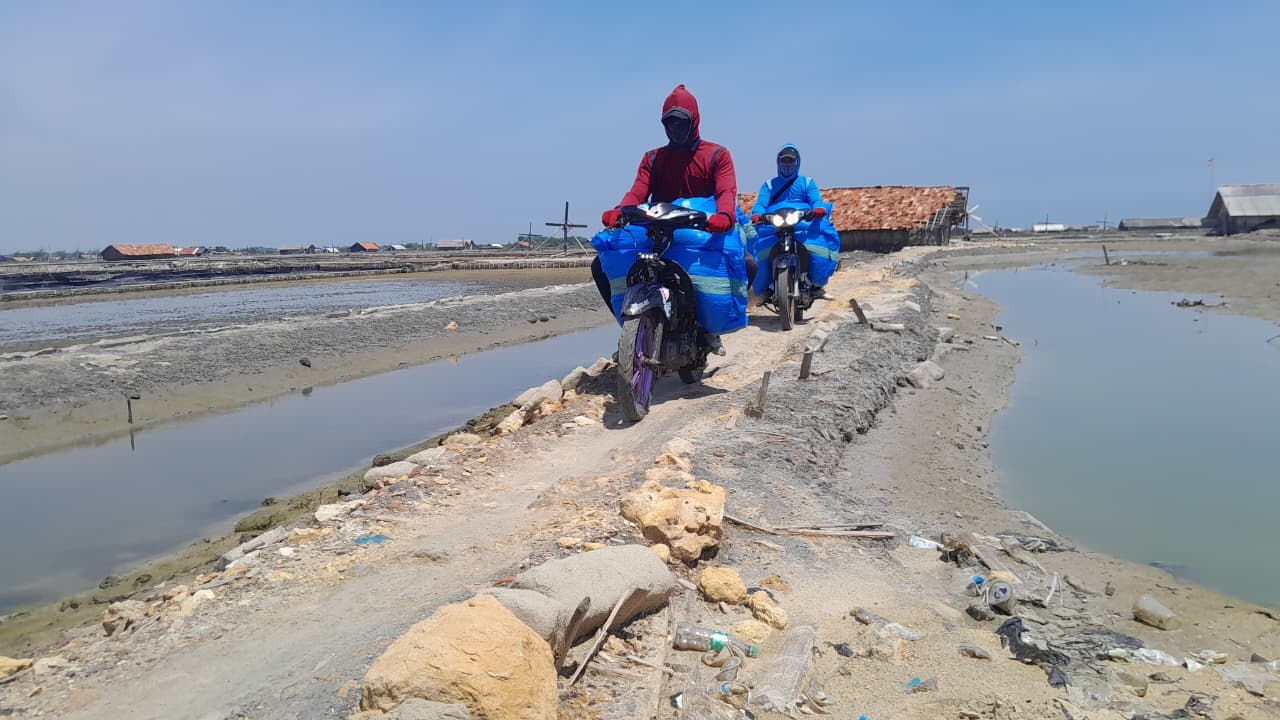 HASIL PRODUKSI: Buruh garam sedang mengangkut garam menggunakan motor di Desa Bunder, Kecamatan Pademawu, Selasa (25/11).