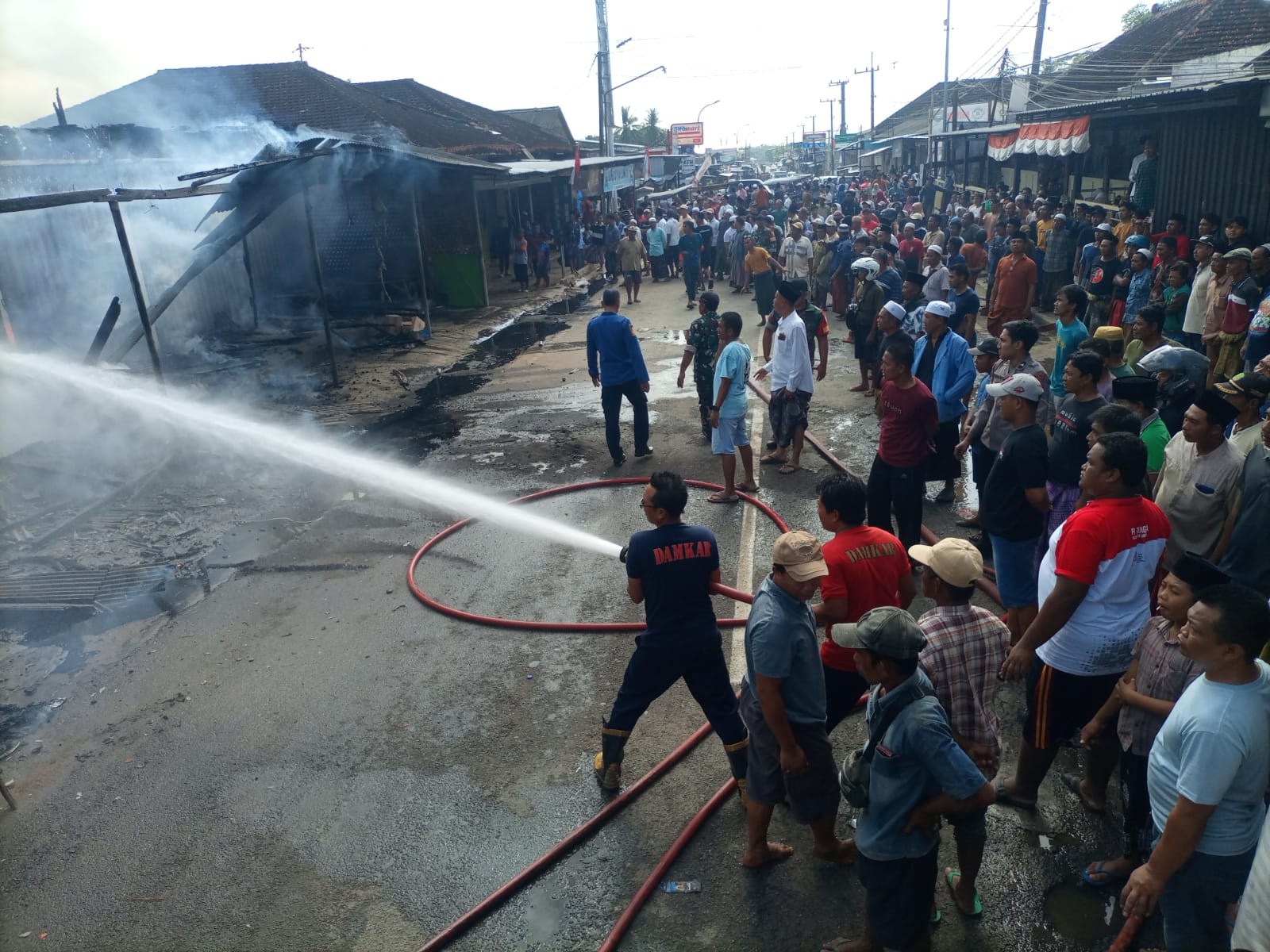 BERJIBAKU: Petugas damkar berusaha memadamkan api yang melalap kios pedagang di Desa Ketawang Laok, Kecamatan Ganding, Sumenep, Kamis (23/10).