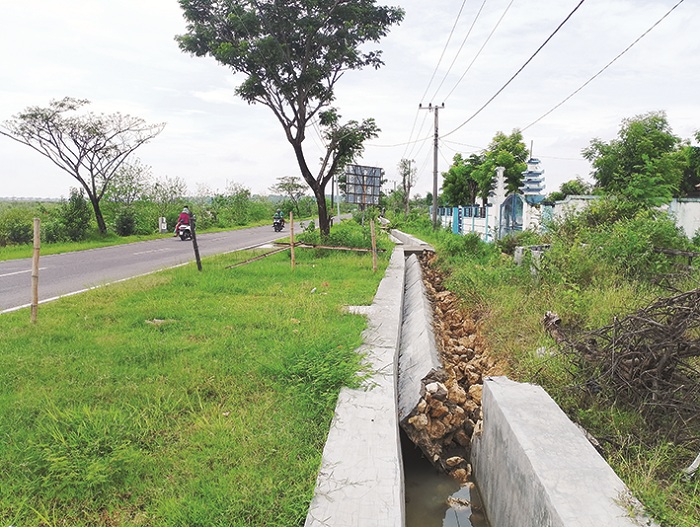 SEBELUM DIPERBAIKI: Pengendara melintas di sekitar proyek saluran di Desa Apaan, Kecamatan Pangarengan, Sampang, yang ambruk Jumat (21/11). (UBAIDILLAHIR RAIE/JPRM)