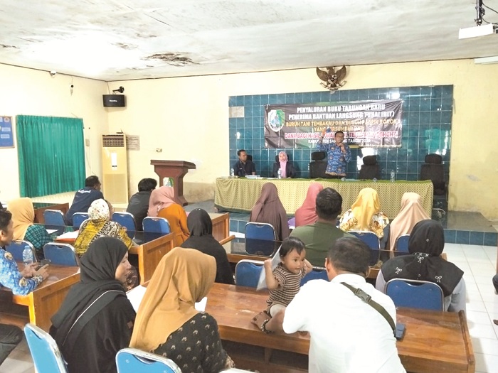 TEPAT SASARAN: Kabid&nbsp;Linjamsos Dinsos PPPA Sampang Erwin Elmi Syahrial menunjukkan butab saat penyaluran BLT DBHCHT kepada buruh tani tembakau Kecamatan Sampang, Senin (1/12). (DINSOS PPPA UNTUK JPRM)