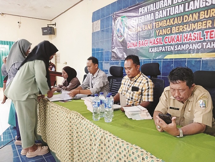TEPAT SASARAN: Petugas Bank Sampang didampingi petugas Dinsos PPPA Sampang menyalurkan butab kepada buruh tani tembakau Kecamatan Sampang di aula kantor dinsos PPPA Selasa (2/12). (DINSOS UNTUK JPRM)