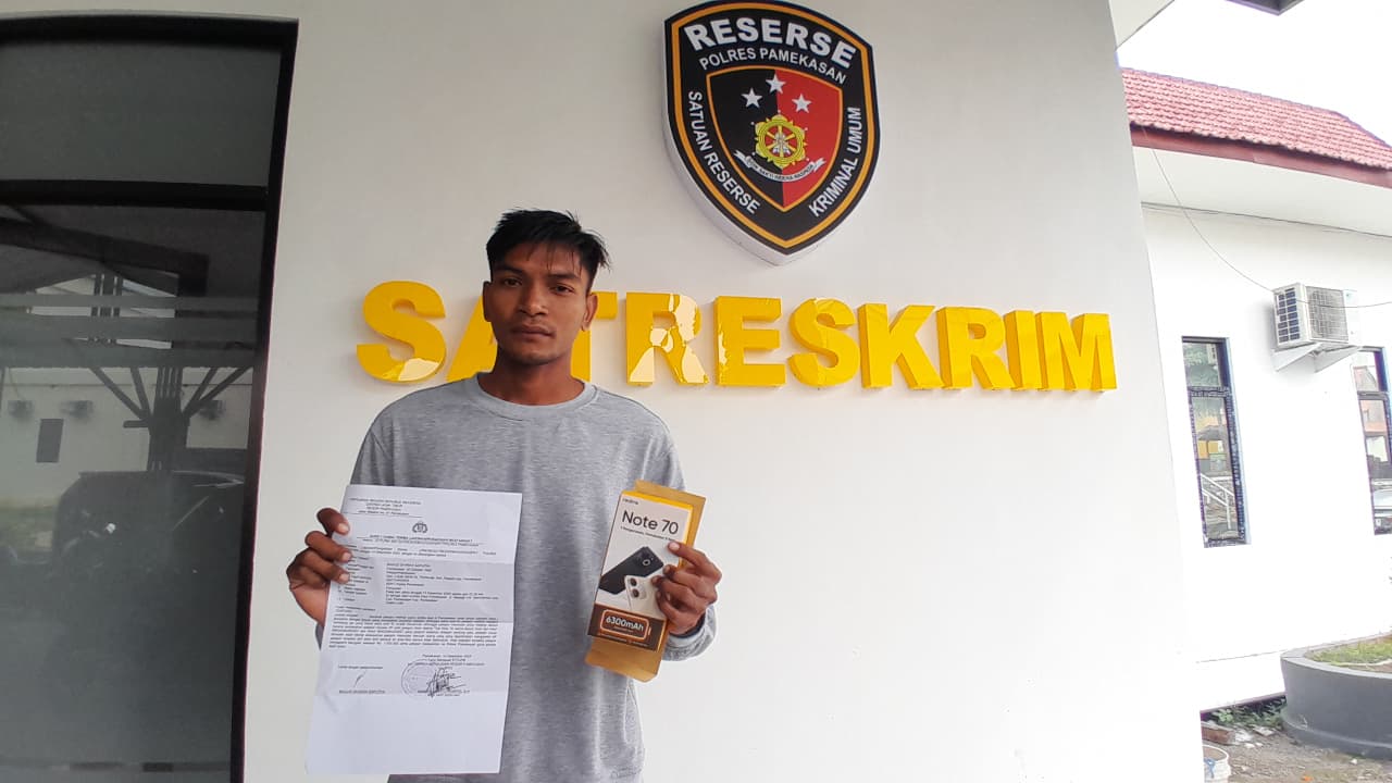 JADI ATENSI: Bagus Okaran Saputra, warga Desa Tlontoraja, Kecamatan Pasean, menunjukkan bukti laporan dan dusbuk HP miliknya di Polres Pamekasan, Minggu (14/12).