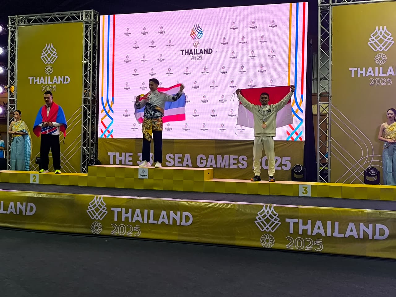 MEMBANGGAKAN: Atlet pencak silat Bangkalan Syarief Hidayatullah Suhaimi (kanan) mengibarkan bendera Indonesia di atas panggung SEA Games Thailand, Minggu (14/12).