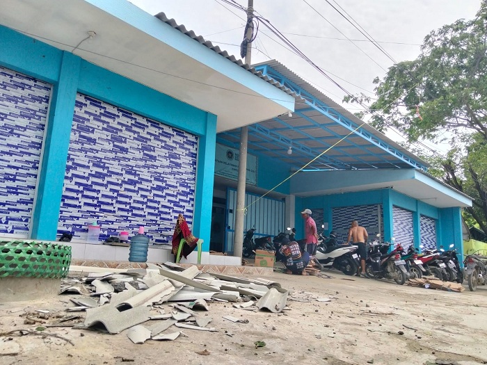 TERDAMPAK PUTING BELIUNG: Pekerja saat menunjukkan atap pada bangunan SPPG yang rusak di Desa Dharma Camplong, Kecamatan Camplong, Sampang, Selasa (16/12). (ANIS BILLAH/JPRM)