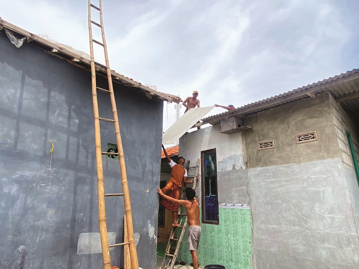 PERISTIWA: Warga saat memperbaiki atap rumahnya yang rusak akibat diterjang puting beliung di Desa Dharma Camplong, Kecamatan Camplong, Sampang, Selasa (16/12). (AYU LATIFAH/JPRM)