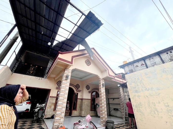 BENCANA: Warga hendak memperbaiki atap rumah yang rusak akibat angin puting beliung di Desa Dharma Camplong, Kecamatan Camplong, Sampang, Selasa (16/12). (AYU LATIFAH/JPRM)