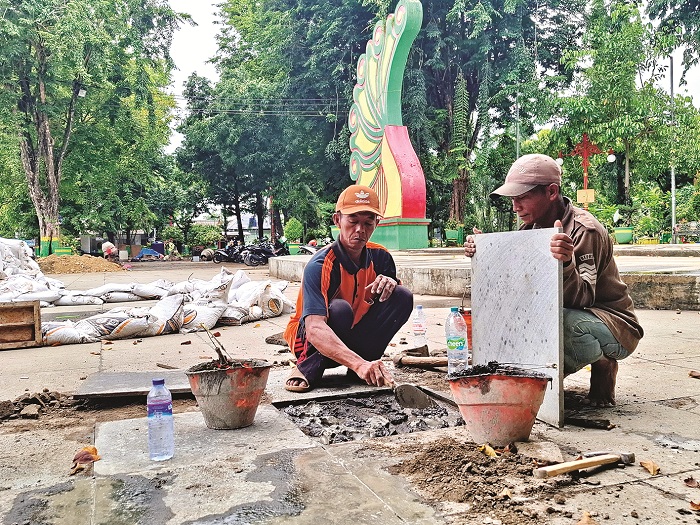 BELUM TUNTAS: Tukang memasang keramik di Taman Bunga Pottre Koneng Sumenep Jumat (19/12). (MOH. LATIF/JPRM)