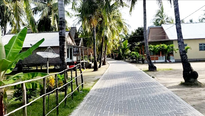 SEJUK: Rumah panggung (kiri) dan tembok milik warga Desa/Pulau Pagerungan Besar, Kecamatan Sapeken, Sumenep, di kanan dan kiri Jalan 2, Selasa (9/12). (LUKMAN HAKIM AG./JPRM)