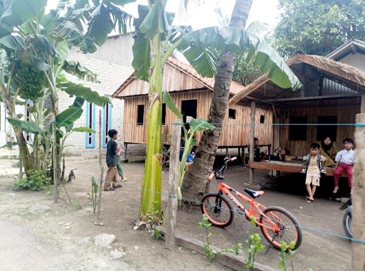 DAMAI: Warga Desa/Pulau Pagerungan Besar, Kecamatan Sapeken, Sumenep, bersantai di depan rumah panggung yang terletak di pinggir Jalan 4, Selasa (9/12). (LUKMAN HAKIM AG./JPRM)