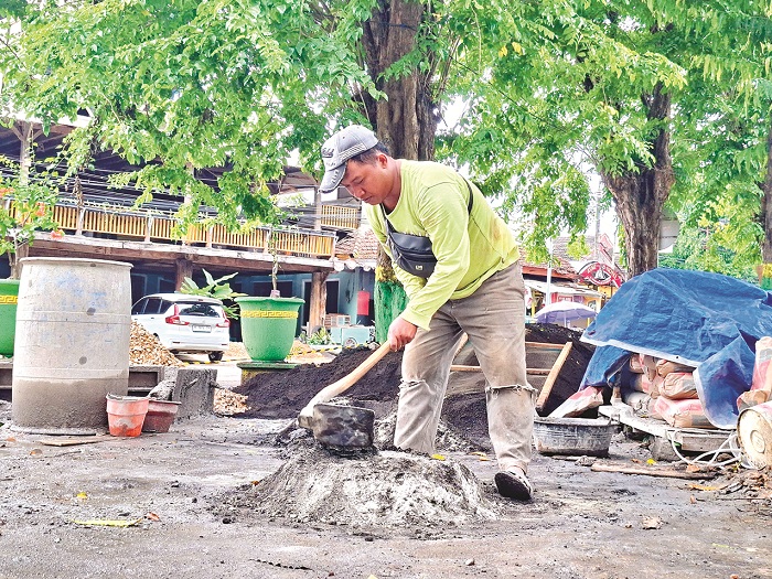 TERANCAM MOLOR: Seorang pekerja tengah mengaduk adonan semen di Taman Bunga Pottre Koneng Sumenep Minggu (21/12). (MOH. LATIF/JPRM)