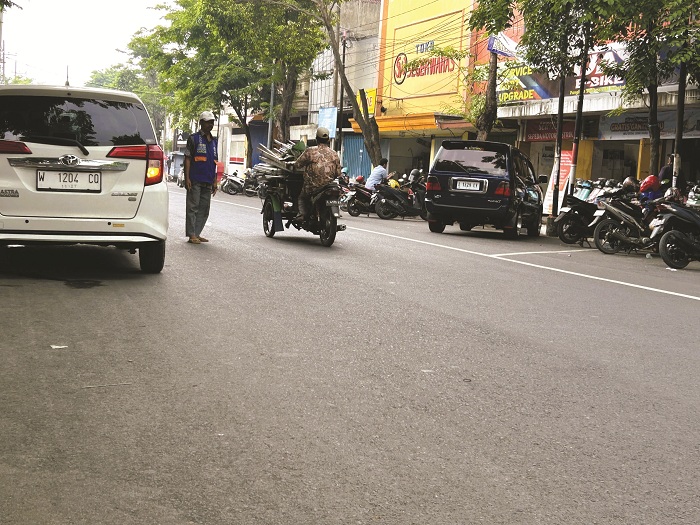 HARUS DIEVALUASI: Juru parkir (jukir) di Jalan Panglima Sudirman Bangkalan tengah mengawal kendaraan Senin (22/12). (VIVIN AGUSTIN HARTONO/JPRM)