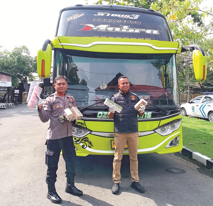 ILEGAL: Plh Kasihumas AKP Eko Puji Waluyo dan KBO Satreskrim Ipda Paundra Kinan Aditama menunjukkan BB yang diamankan dari bus di halaman Mapolres Sampang saat konferensi pers Selasa (23/12).