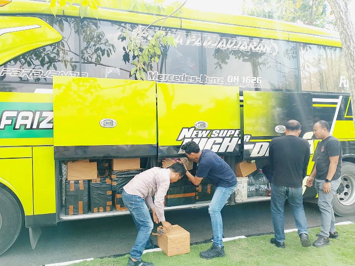 MELANGGAR HUKUM: Polisi memeriksa BB rokok ilegal dari bagasi bus pariwisata yang diparkir di Mapolres Sampang Selasa (23/12). (UBAIDILLAHIR RAIE/JPRM)