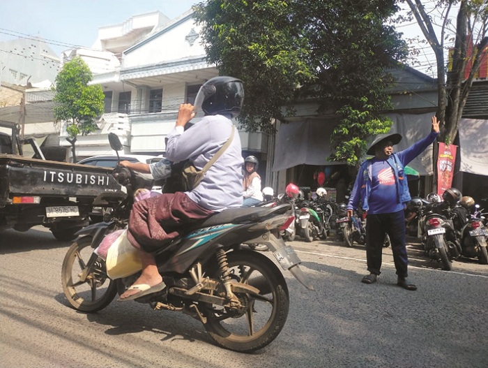 DIAWASI KETAT: Jukir di ruas Jalan Panglima Sudirman Bangkalan sedang mengawal kendaraan pada Minggu (28/12). (VIVIN AGUSTIN HARTONO/JPRM)