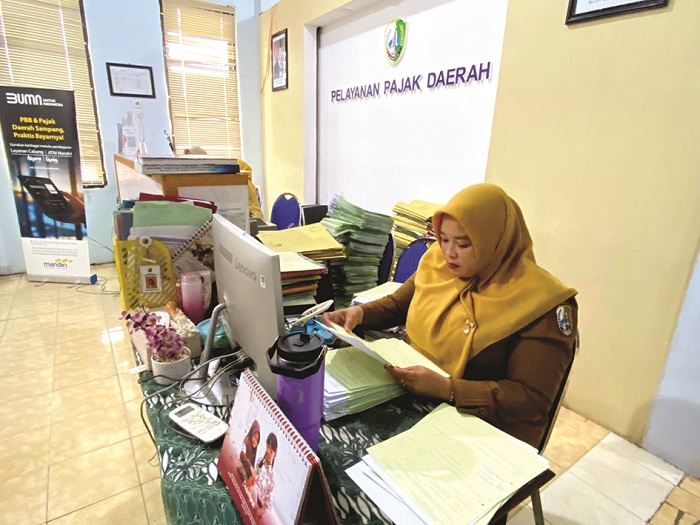 FOKUS: Petugas saat mencatat bukti pembayaran pajak di kantor BPPKAD Sampang kemarin. (AYU LATIFAH/JPRM)
