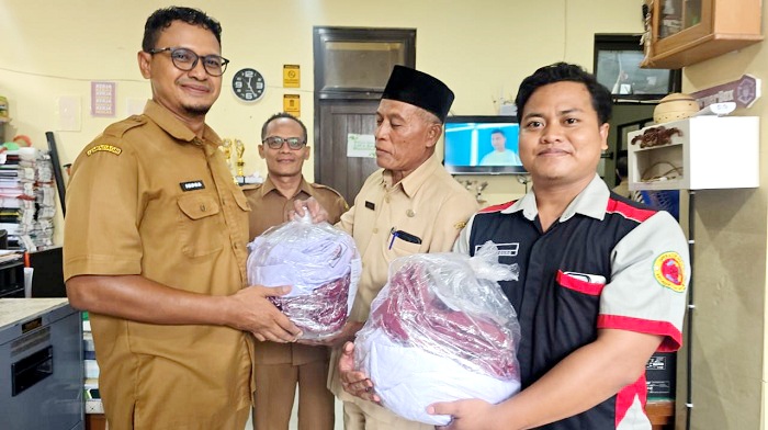 MENERIMA: Kepala SDN 1 Gunggung, Kecamatan Bantuan, Sumenep, (berkopiah) menerima bantuan seragam di kantor dinas setempat, Selasa (6/1). (DISPENDIK UNTUK JPRM)