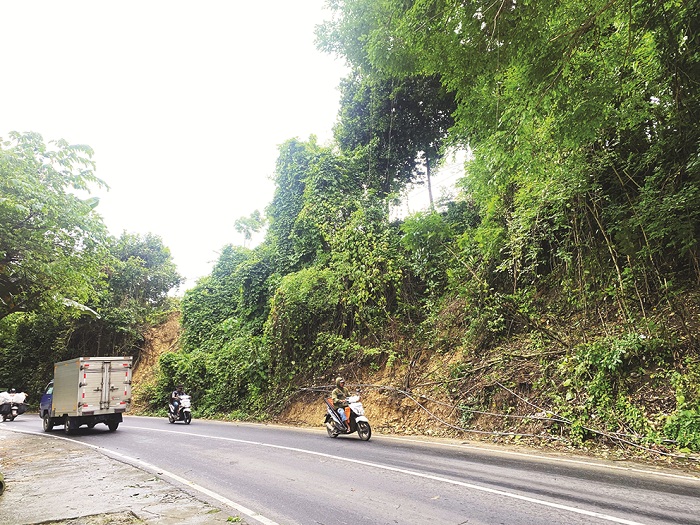 HATI-HATI: Pengendara bermotor melintas di sekitar area bekas tebing longsor di Jalan Raya Pakong-Waru, Pamekasan, Senin (12/1). (MOH. IQBAL AFGANI/JPRM)
