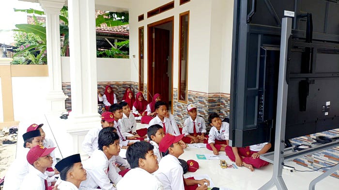 TAK REPRESENTATIF: Puluhan siswa SDN Tlagah 2 Bangkalan mengikuti KBM di teras rumah warga Selasa (13/1). (FATMAWATI UNTUK JPRM)
