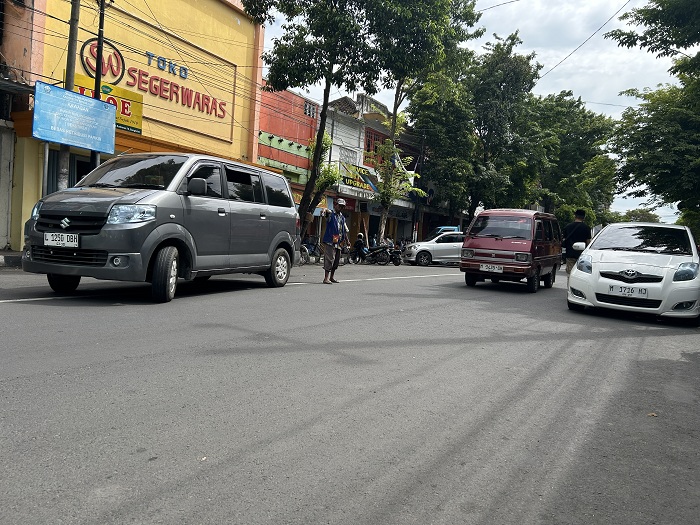 LENGANG: Jukir mengatur kendaraan di Jalan Panglima Sudirman Selasa (13/1). (VIVIN AGUSTIN HARTONO/JPRM)