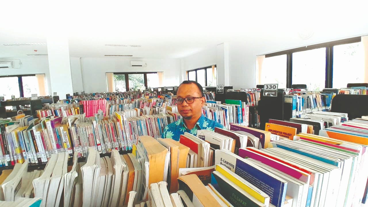 JENDELA DUNIA: Pustakawan Perpusda M. Tabrani Pamekasan Kusairi sedang mengecek koleksi buku yang tersimpan di rak Kamis (15/1). (M. KHOLIL RAMLI/JPRM)