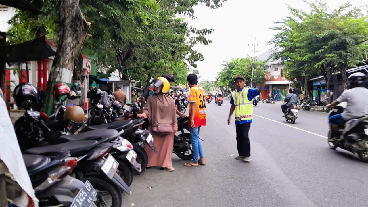 SUMBER PAD: Jukir sedang mengatur kendaraan di Jalan Diponegoro, Kecamatan Kota Pamekasan, Kamis (15/1).