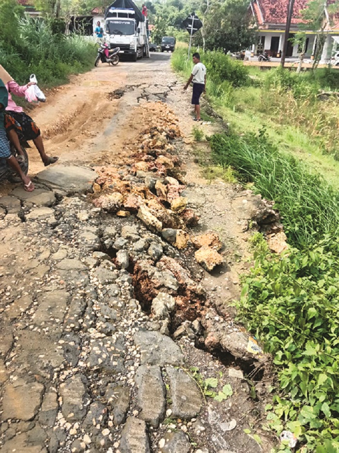 MEMBAHAYAKAN: Warga berada di lokasi jalan longsor di Dusun Banda, Bira Tengah, Kecamatan Sokobanah, Sampang, Sabtu (17/1). (SALIM UNTUK JPRM)