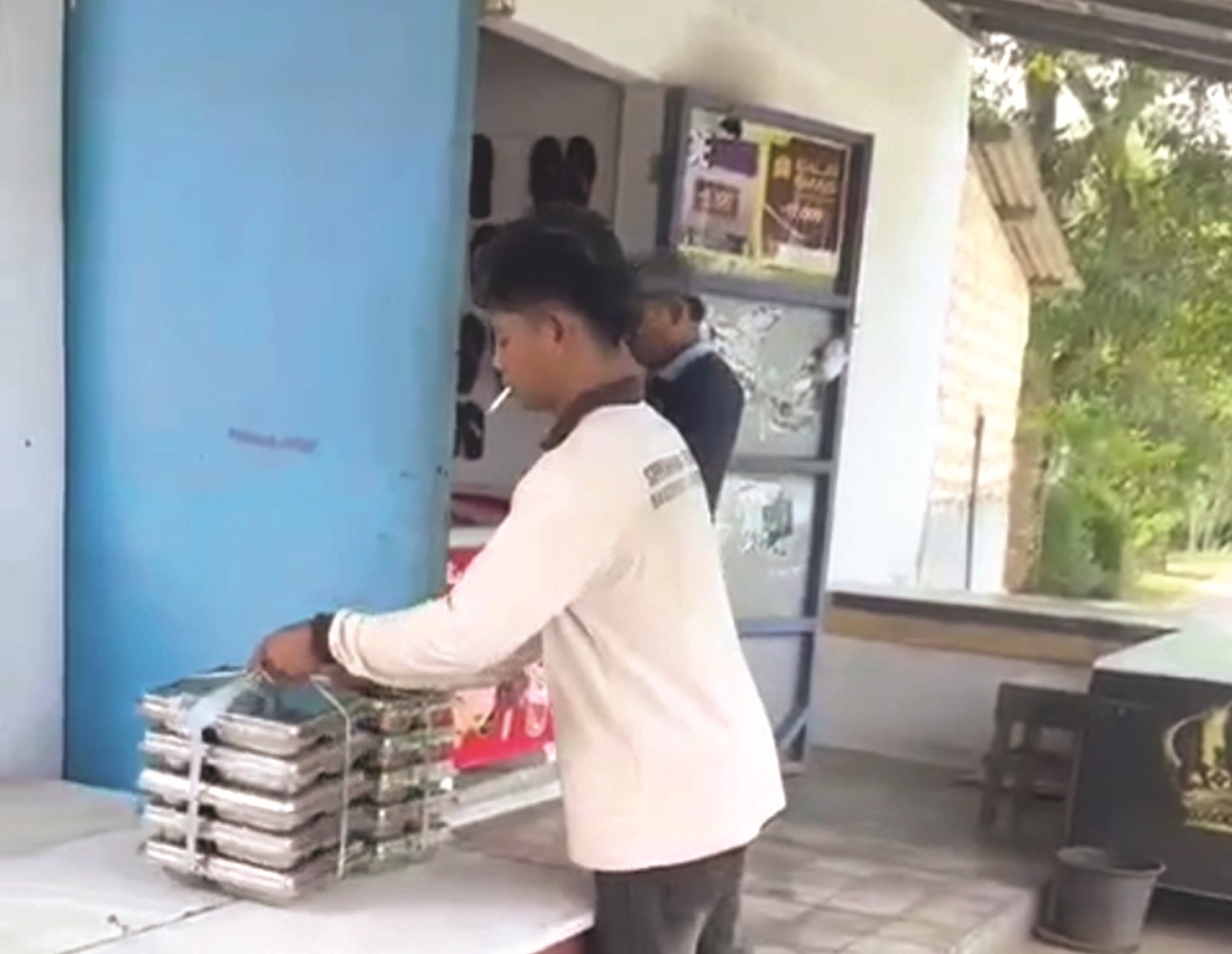 JANGGAL: Petugas SPPG menurunkan MBG dan diletakkan di rumah warga di Desa Batuporo Timur, Kecamatan Kedungdung, Sampang, Selasa (20/1).