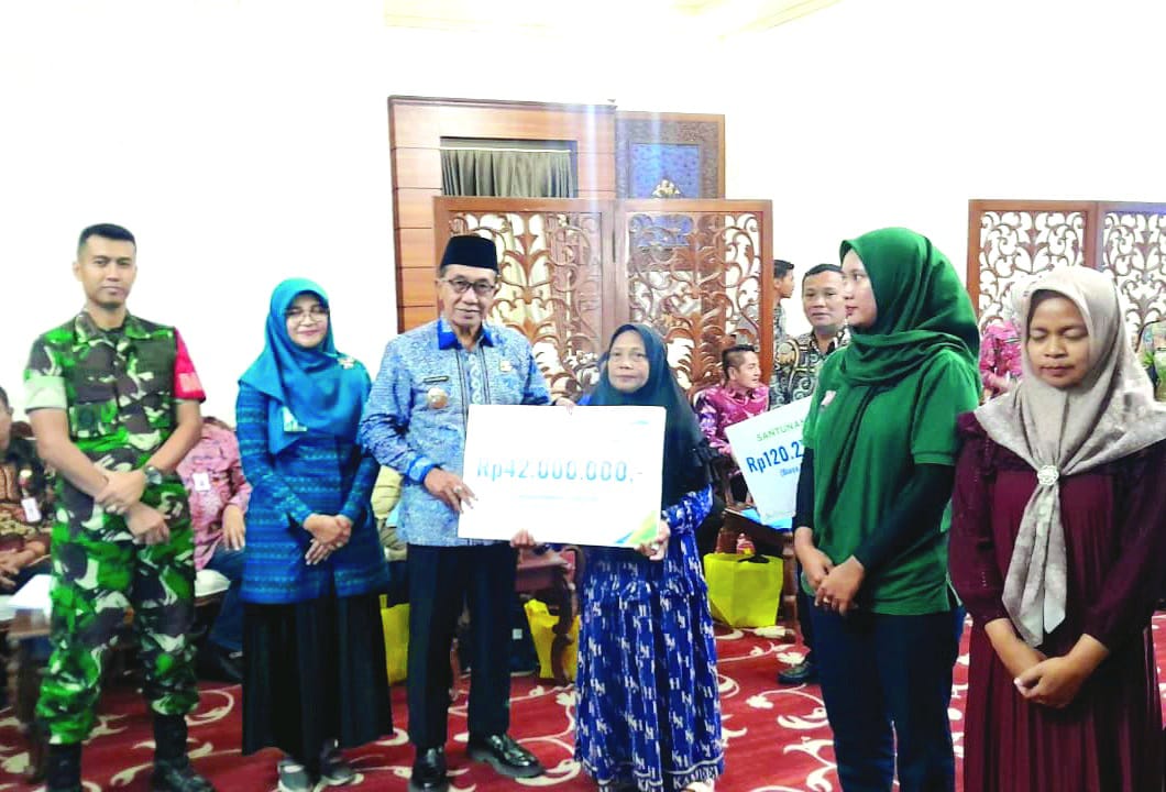SIMBOLIS: Bupati Pamekasan KH Kholilurrahman memberikan JKK BPJS Ketenagakerjaan kepada penerima manfaat di Peringgitan Dalam Pendopo Ronggosukowati Kamis (22/1). (M. KHOLIL RAMLI/JPRM)